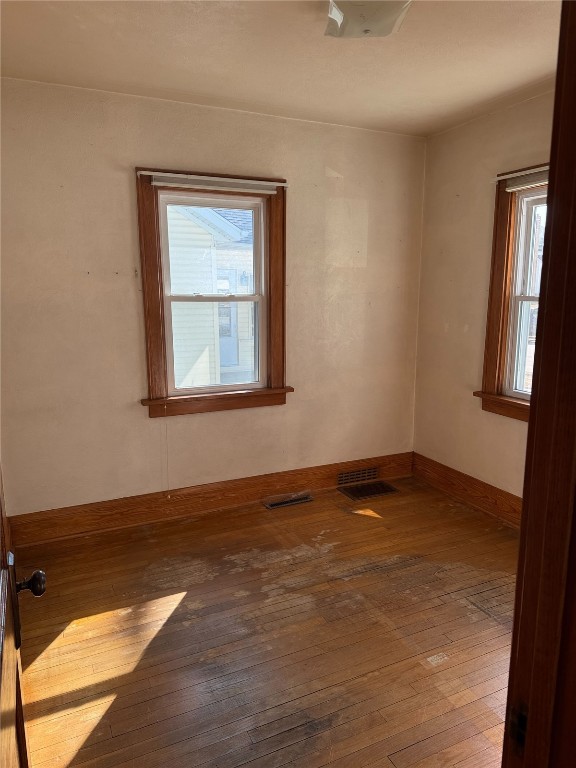 spare room featuring visible vents, baseboards, and hardwood / wood-style floors