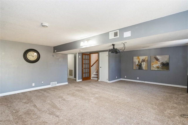 carpeted empty room featuring visible vents, stairs, and baseboards