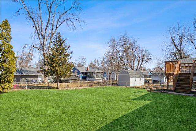 view of yard featuring an outbuilding, a deck, fence, stairway, and a storage shed