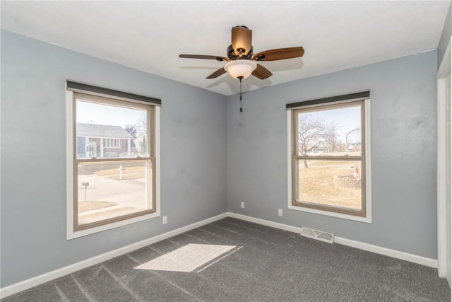 empty room with a ceiling fan, baseboards, visible vents, and dark carpet