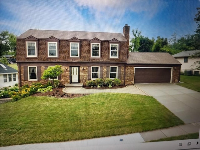 view of front facade with concrete driveway, a front yard, an attached garage, brick siding, and a chimney