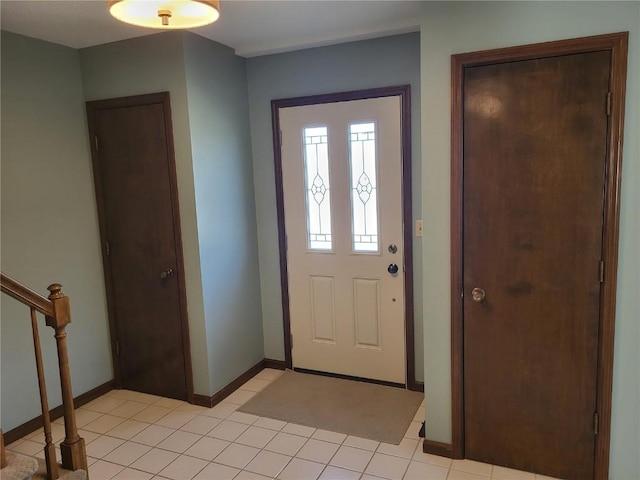 foyer entrance featuring light tile patterned floors, stairs, and baseboards