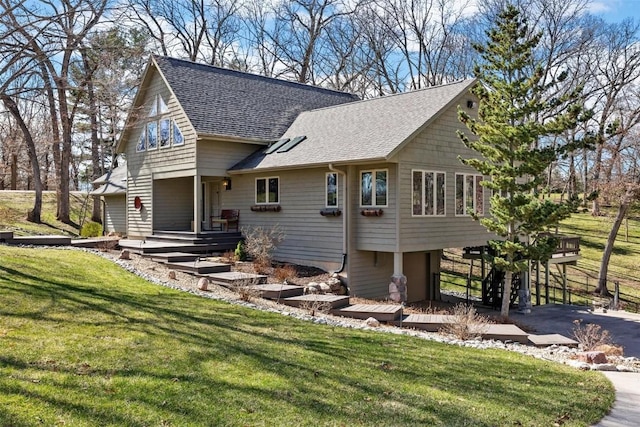 view of front facade with driveway, a shingled roof, and a front yard