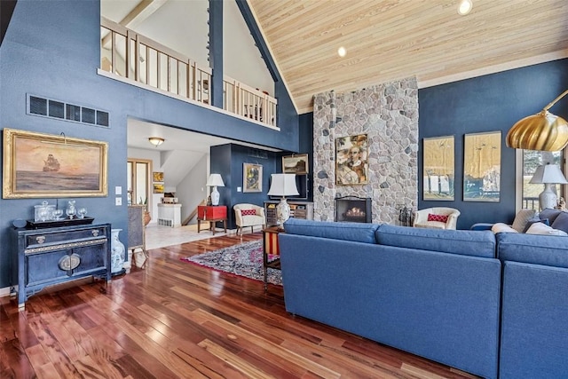 living room featuring visible vents, a stone fireplace, wooden ceiling, wood finished floors, and high vaulted ceiling