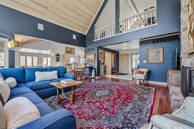 living area with baseboards, wood ceiling, a fireplace, wood finished floors, and high vaulted ceiling