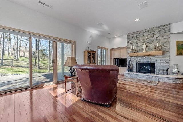 living room featuring visible vents, recessed lighting, a stone fireplace, and wood finished floors