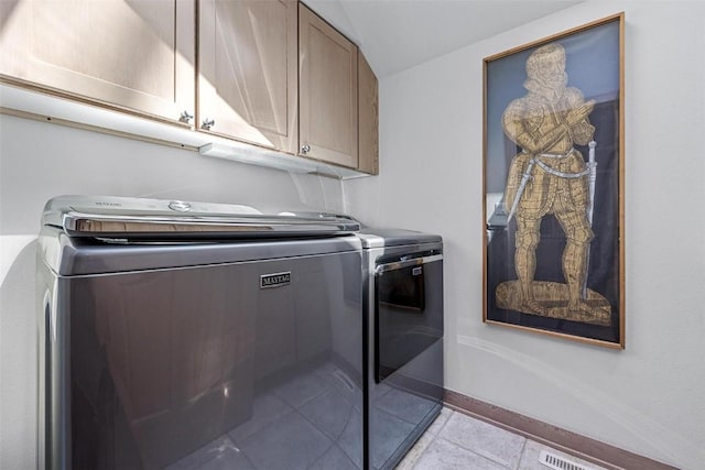 clothes washing area featuring cabinet space, light tile patterned floors, washing machine and dryer, and baseboards