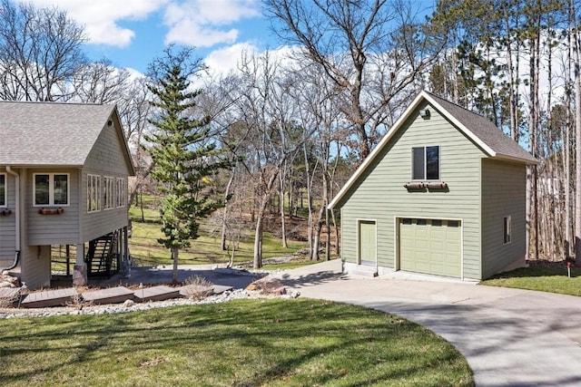 view of home's exterior with stairway, a lawn, a detached garage, and roof with shingles