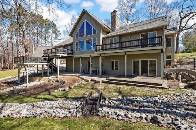 back of house featuring a deck, stairway, and a chimney