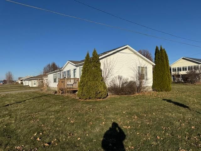 view of property exterior with a lawn and a deck