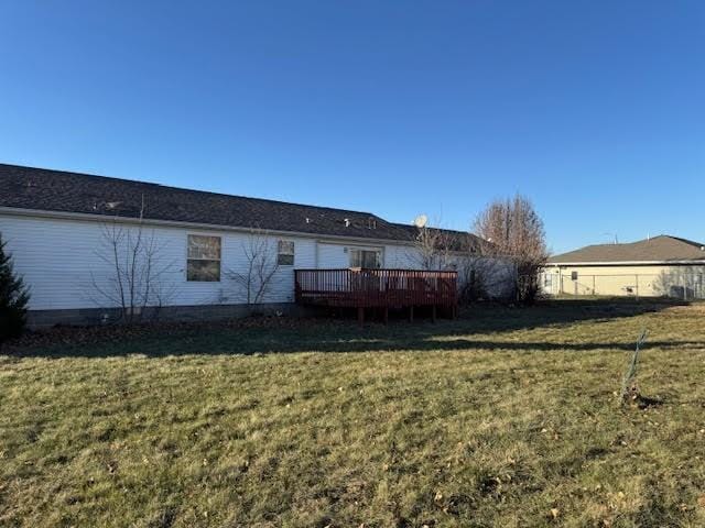 rear view of property featuring a deck, a yard, and fence