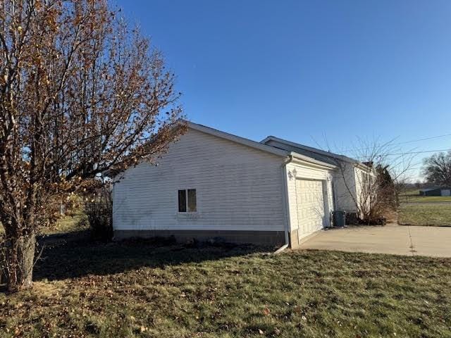 view of home's exterior with an attached garage, a yard, and driveway