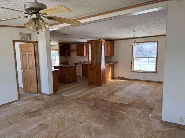 unfurnished living room with ceiling fan, a textured ceiling, baseboards, and ornamental molding