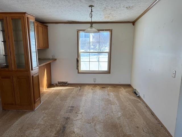 unfurnished dining area with a textured ceiling and ornamental molding