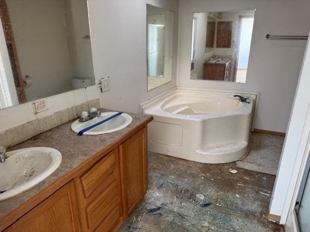 bathroom featuring double vanity, a bath, and a sink