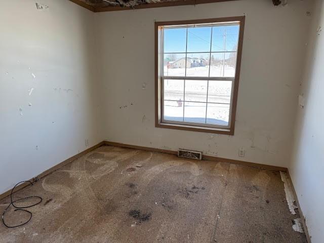 unfurnished room with baseboards and visible vents