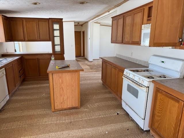 kitchen featuring brown cabinetry, white appliances, a center island, and a textured ceiling