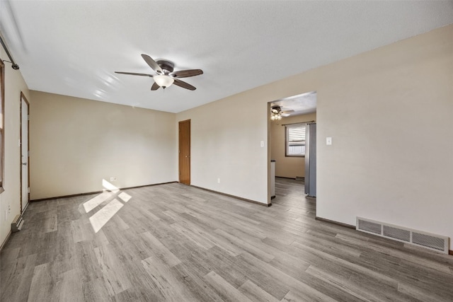 empty room featuring ceiling fan, visible vents, baseboards, and light wood-style flooring