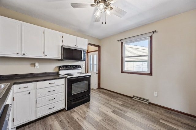 kitchen featuring black / electric stove, dark countertops, visible vents, stainless steel microwave, and light wood-type flooring