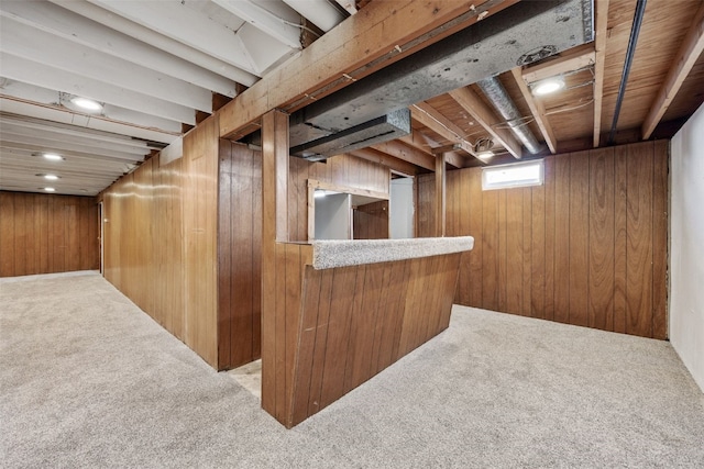 basement with wooden walls, a dry bar, and carpet flooring