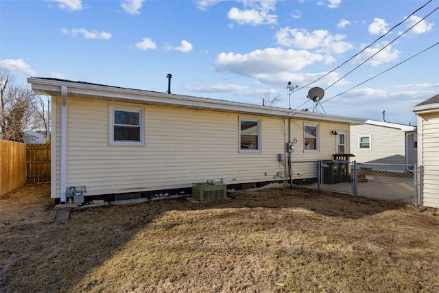 rear view of house with a lawn, central AC unit, and fence private yard