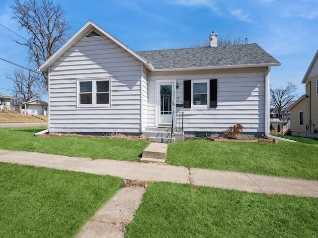 bungalow featuring a chimney, roof with shingles, and a front lawn