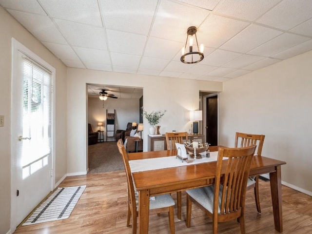 dining space with a paneled ceiling, light wood-type flooring, and baseboards