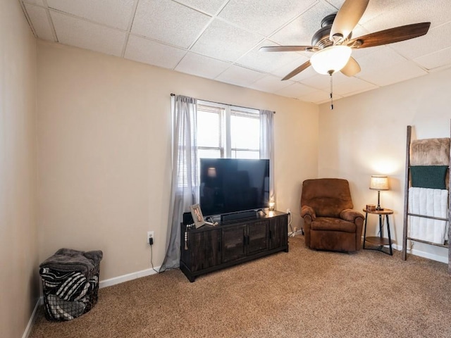 sitting room featuring a drop ceiling, baseboards, carpet floors, and a ceiling fan