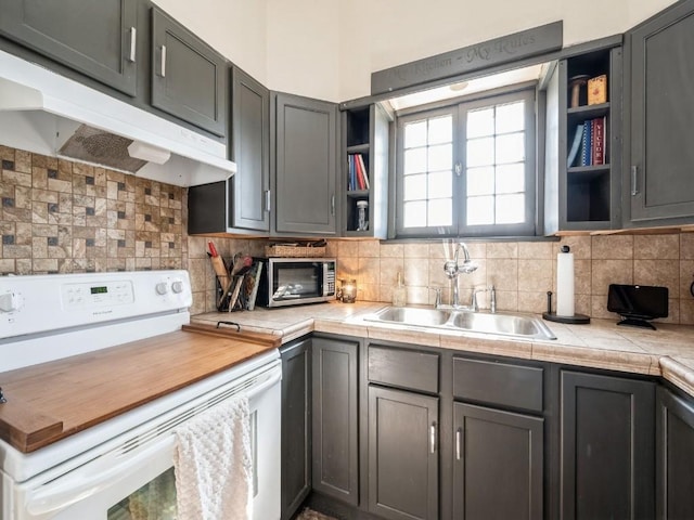 kitchen with electric range, a sink, open shelves, under cabinet range hood, and tasteful backsplash