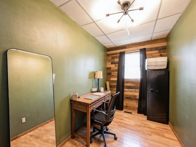 office space with wood walls, a paneled ceiling, and light wood-style floors