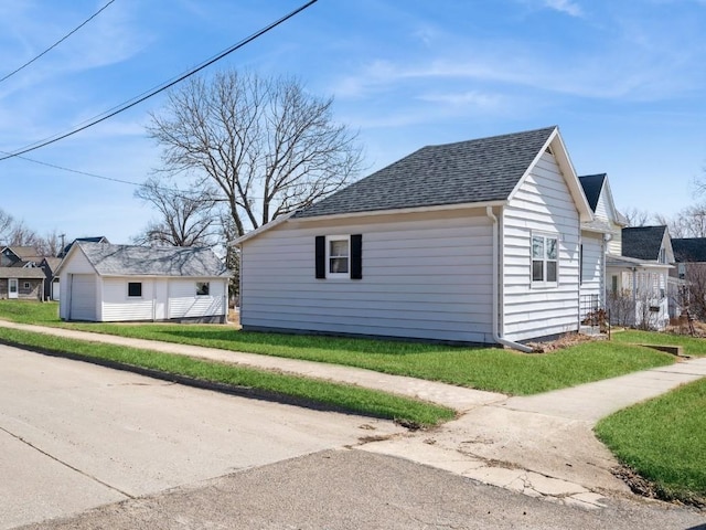 view of property exterior with a detached garage, a lawn, roof with shingles, and an outdoor structure