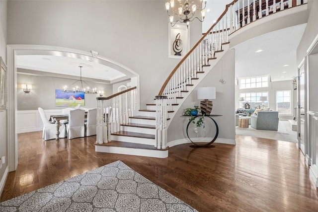 foyer entrance with a notable chandelier, a high ceiling, wood finished floors, and stairs