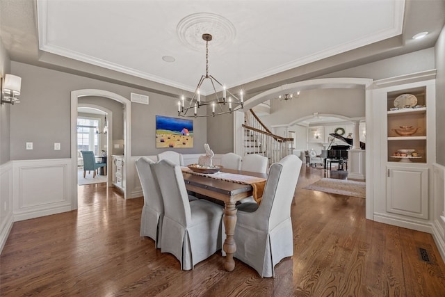 dining area featuring visible vents, arched walkways, wainscoting, and dark wood-style flooring