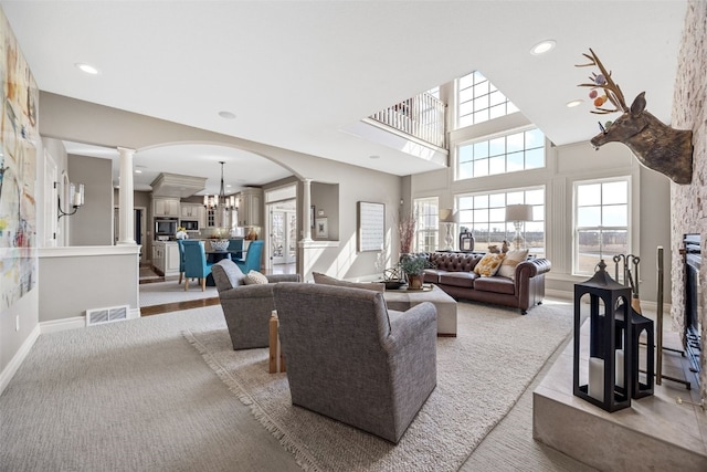 living area with visible vents, light colored carpet, ornate columns, and a glass covered fireplace