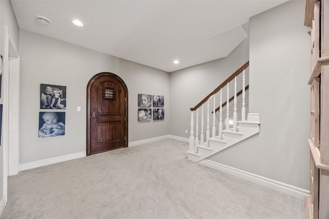 carpeted foyer entrance with arched walkways, stairway, recessed lighting, and baseboards