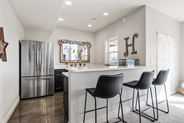 kitchen with light countertops, a breakfast bar area, recessed lighting, and freestanding refrigerator