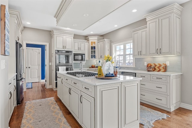 kitchen featuring wood finished floors, recessed lighting, stainless steel appliances, light countertops, and a center island