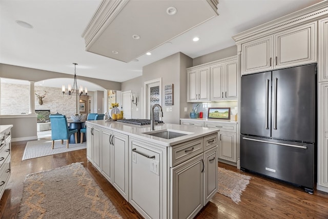 kitchen with dark wood-style flooring, arched walkways, freestanding refrigerator, and a sink