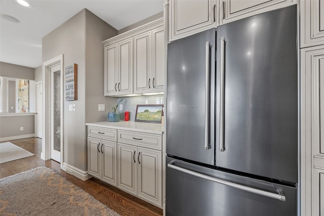 kitchen with tasteful backsplash, baseboards, dark wood finished floors, light countertops, and high quality fridge