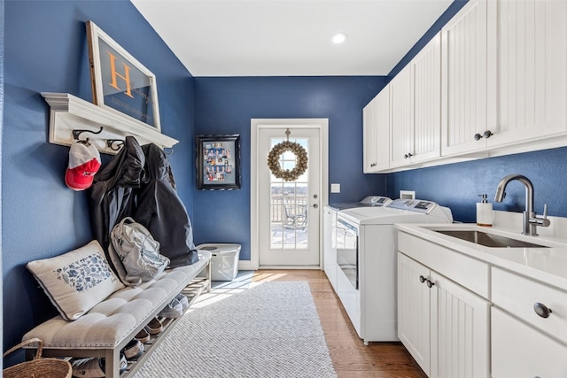 laundry room with a sink, cabinet space, light wood-style flooring, and washing machine and clothes dryer