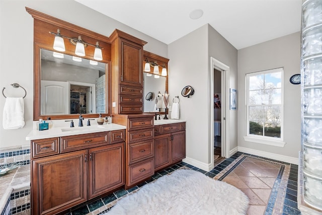 full bathroom featuring a sink, a walk in closet, baseboards, and double vanity