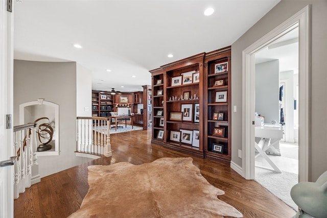 interior space featuring a ceiling fan, wood finished floors, recessed lighting, and an upstairs landing