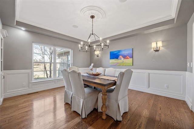 dining room with visible vents, a wainscoted wall, a tray ceiling, wood finished floors, and a notable chandelier