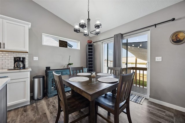 dining area with baseboards, dark wood-type flooring, an inviting chandelier, and vaulted ceiling