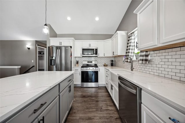 kitchen featuring dark wood finished floors, lofted ceiling, a sink, appliances with stainless steel finishes, and backsplash