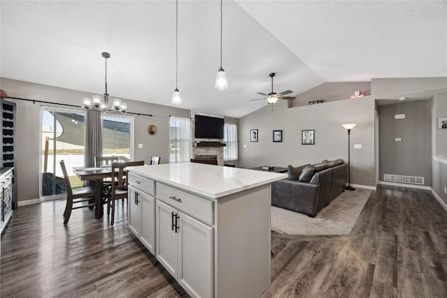 kitchen with dark wood finished floors, lofted ceiling, visible vents, and a center island