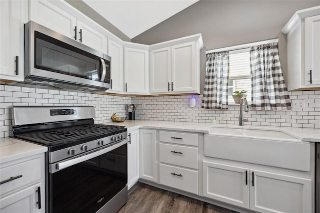 kitchen with white cabinets, stainless steel appliances, lofted ceiling, and a sink