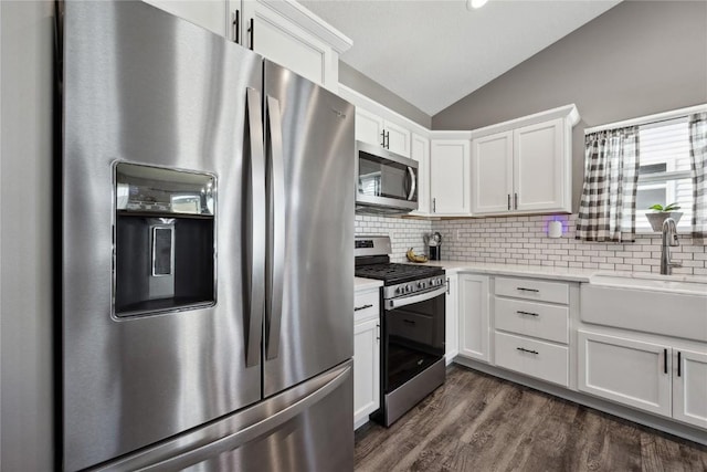 kitchen with light countertops, lofted ceiling, decorative backsplash, appliances with stainless steel finishes, and a sink