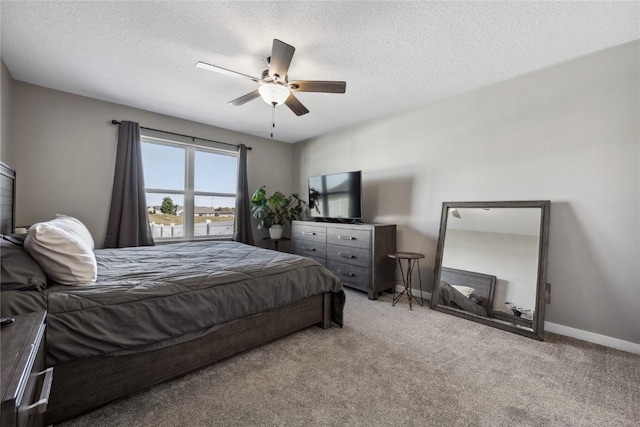 carpeted bedroom featuring ceiling fan, a textured ceiling, and baseboards