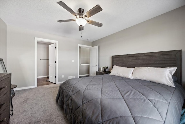 carpeted bedroom with visible vents, baseboards, a textured ceiling, and ceiling fan